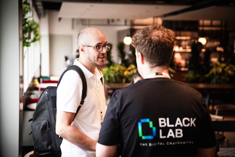 A black lab team member Ady stood chatting to a client at a Digital Leaders' Collective Event
